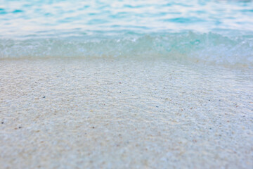 A beach with a large wave crashing into the shore