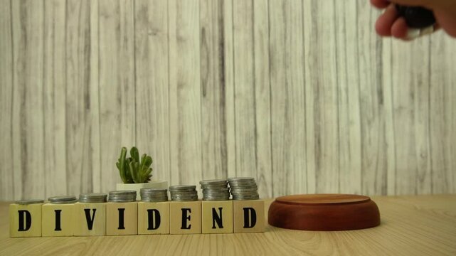 Slow Motion video of annual General Meeting decide Dividend Yield by knocking the gavel. Dividend Concept with Coins, Gavel, and Wooden Blocks Spelling Dividends