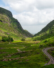 Breathtaking vista. winding road carves path through vibrant green Irish landscape, mountains framing valley.