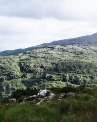 Lush green mountainous area in County Kerry, Ireland. Rolling hills and sparse vegetation give way to rocks and grass near the head of the Gap of Dunloe.