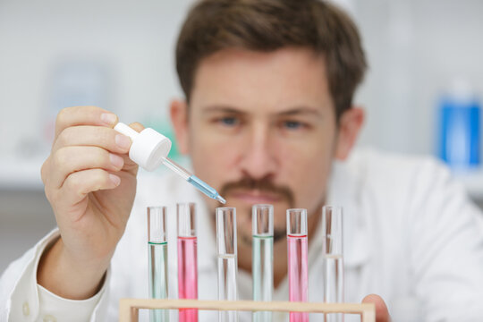 male research scientist uses pipette and tubes in a laboratory