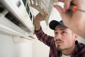 concentrated man is fixing air conditioning