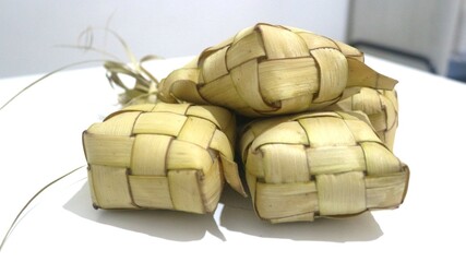 Traditional ketupat woven from young coconut leaves, commonly served during Eid al-Fitr and festive celebrations in Indonesia. Cultural food background.