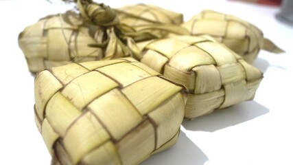 Traditional ketupat woven from young coconut leaves, commonly served during Eid al-Fitr and festive celebrations in Indonesia. Cultural food background.