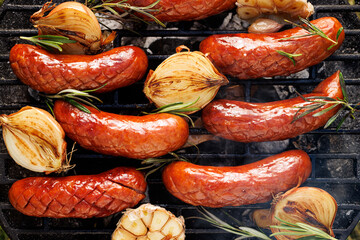 Grilled pork sausages with addition onion and garlic on a cast iron grill,  top view