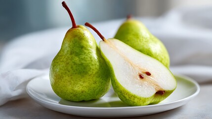 Fresh Green Pears on a White Plate, One Sliced in Half