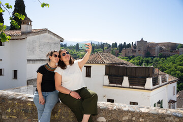 Tourists taking selfie with alhambra palace in background, granada, spain