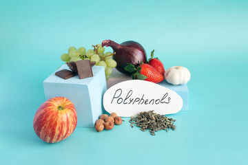 Products containing useful polyphenols in their composition. Grapes, onions, garlic, chocolate and other products in close-up on a light background and the inscription on paper "polyphenols".