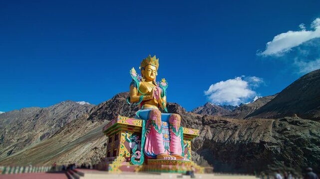 A majestic statue of Maitreya Buddha seated in a meditative pose against the backdrop of the rugged Himalayas and a clear blue sky. This vibrant monument, located in Diskit Monastery, Nubra Valley,