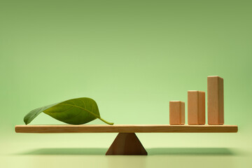 Sustainable, Green investment, financial, and eco-friendly economic growth. Wooden Bar Graph and a Green Leaf balanced on a scale