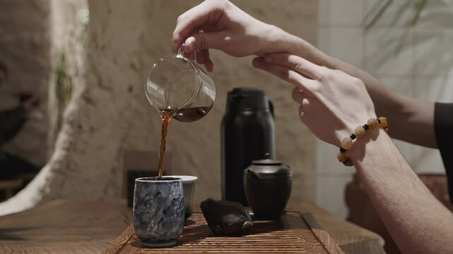 This calm and intentional moment shows the final step in a tea ritual &mdash; serving tea into bowls for tasting.