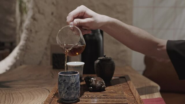 This calm and intentional moment shows the final step in a tea ritual &mdash; serving tea into bowls for tasting.