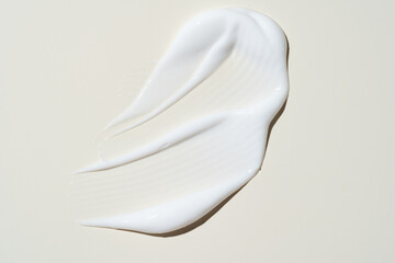 White cosmetic cream texture, skincare lotion swatch on light beige background. Face creme, body moisturizer, hair conditioner smear smudge stroke. Creamy beauty product closeup