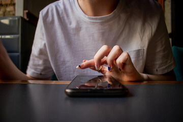 Close up of women's hands holding cell telephone with blank copy space scree for your advertising text message or promotional content, hipster girl watching video on mobile phone during coffee break