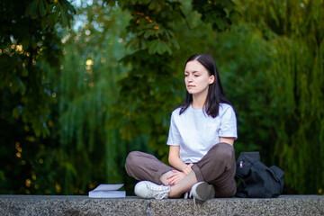 A girl meditates in the Lotus position in the fresh air in the Park. The girl relaxes after yoga. Back view, space for text
