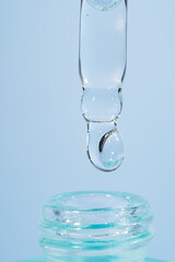 A drop of cosmetic oil falls from the pipette to the glass bottle. Skin care cosmetics design package. Hyaluronic or vitamin C serum for damaged skin