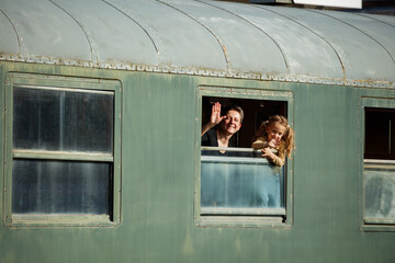 Mother with kid wave from train window in warm afternoon light