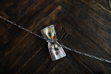 Secure Money Concept Showing Dollar Bills Bound with Chain on Wooden Surface