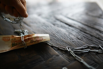 Hand Chaining Russian Ruble Banknotes on Wooden Surface - Concept of Financial Constraints