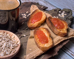 Rustic breakfast scene with a black enamel mug of coffee, toasted bread with tomato, rolled oats, and wooden textures, evoking a cozy, natural morning vibe