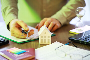 Real Estate Agent with Keys and House Model on Desk