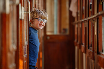 Boy peeks behind polished doors in historic railway corridor