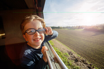 Young boy leans eagerly from carriage window to feel cool breeze