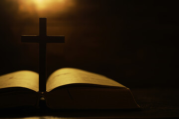 Silhouette of Cross on Open Bible with Warm Light Background