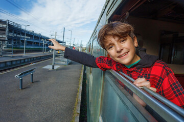 Teen boy points excitedly out of train window at passing tracks