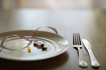 Pharmaceutical Pills on a Plate with Fork, Knife, and Measuring Tape Emphasizing Weight Loss and Diet