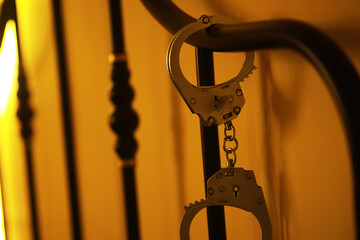 Handcuffs Secured to Bed Frame in Dim Ambient Light