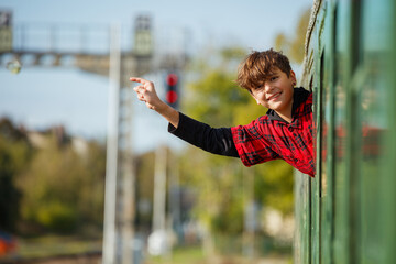 Through the open window of a train car, teenage boy looking out