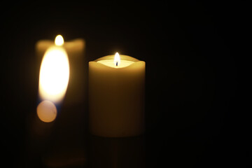 Illuminated Candle in Dark Background: Warm Light and Peaceful Ambience