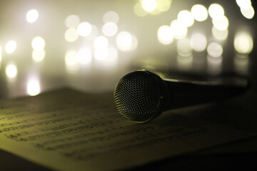Obraz premium Vintage Microphone on Sheet Music Surrounded by Bokeh Lights