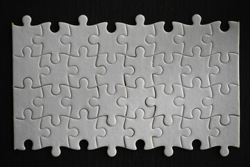 Closeup of Incomplete White Puzzle Pieces on Black Background Symbolizing Challenge and...