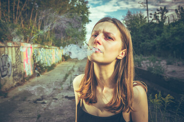 Portrait of a stylish woman holding a cigarette, standing outdoors in soft natural light....
