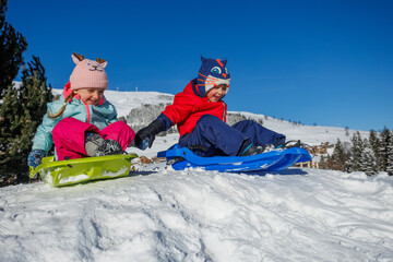 Joyful children sledding on a snowy hill, bundled and happy