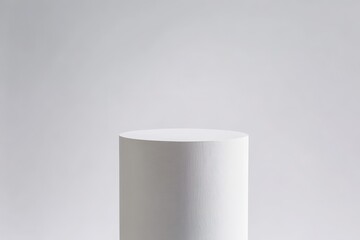 A white cylindrical podium against a plain white background showcases minimalist elegance and a modern aesthetic, perfect for product displays or awards ceremonies.