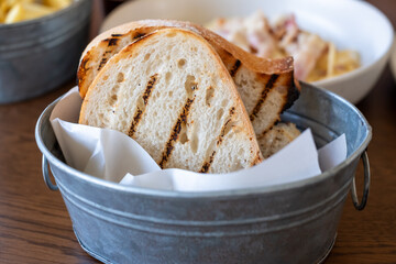 Grilled Bread in Metal Basket on Wooden Table