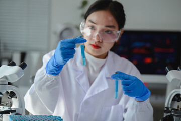 Scientist wearing lab coat and gloves comparing two test tubes with blue liquid in a laboratory