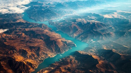 Aerial view of a winding river flowing through rugged mountains, showcasing vibrant blue waters and earthy tones of the landscape, capturing the beauty of nature's topography