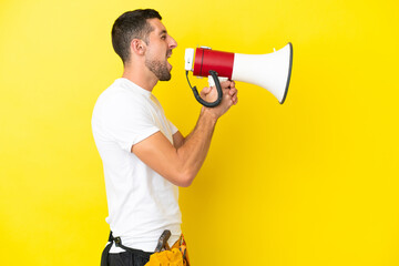 young electrician caucasian man isolated on yellow background shouting through a megaphone
