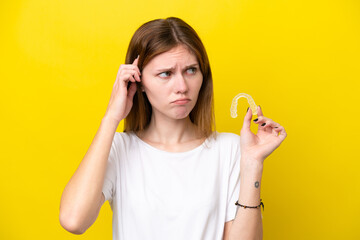 Young English woman holding invisible braces having doubts and thinking