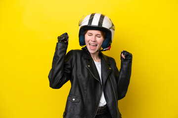 Young English woman with a motorcycle helmet isolated on yellow background celebrating a victory