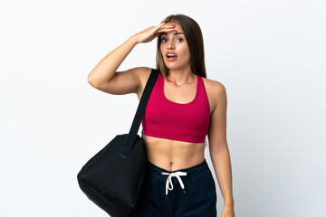 Young sport Uruguayan woman with sport bag isolated on white background doing surprise gesture while looking to the side