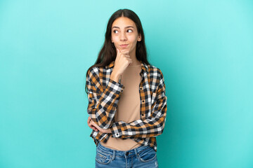 Young French woman isolated on blue background thinking an idea while looking up