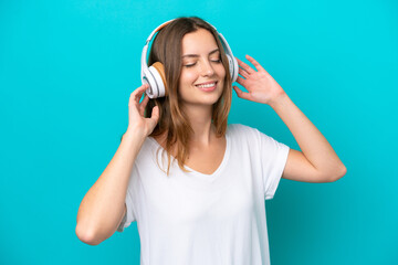Fototapeta premium Young caucasian woman isolated on blue background listening music and singing