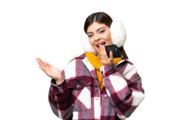 Young Russian woman wearing winter muffs over isolated chroma key background keeping a conversation with the mobile phone with someone