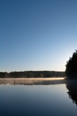 Calm Lake at Sunrise with Light Fog and Woodland