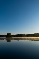 Calm Lake at Sunrise with Light Fog and Woodland